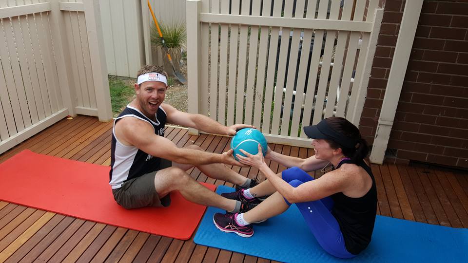 A husband and wife doing sit ups together with a weighted ball